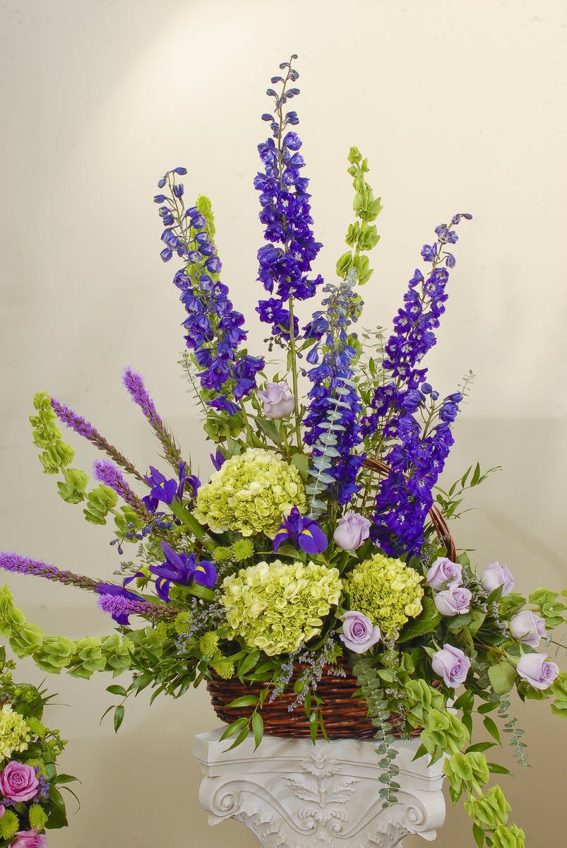 Basket design featuring roses and hydrangea in a mix of purple, green, and blue hues. Approximate size for the standard design is 20