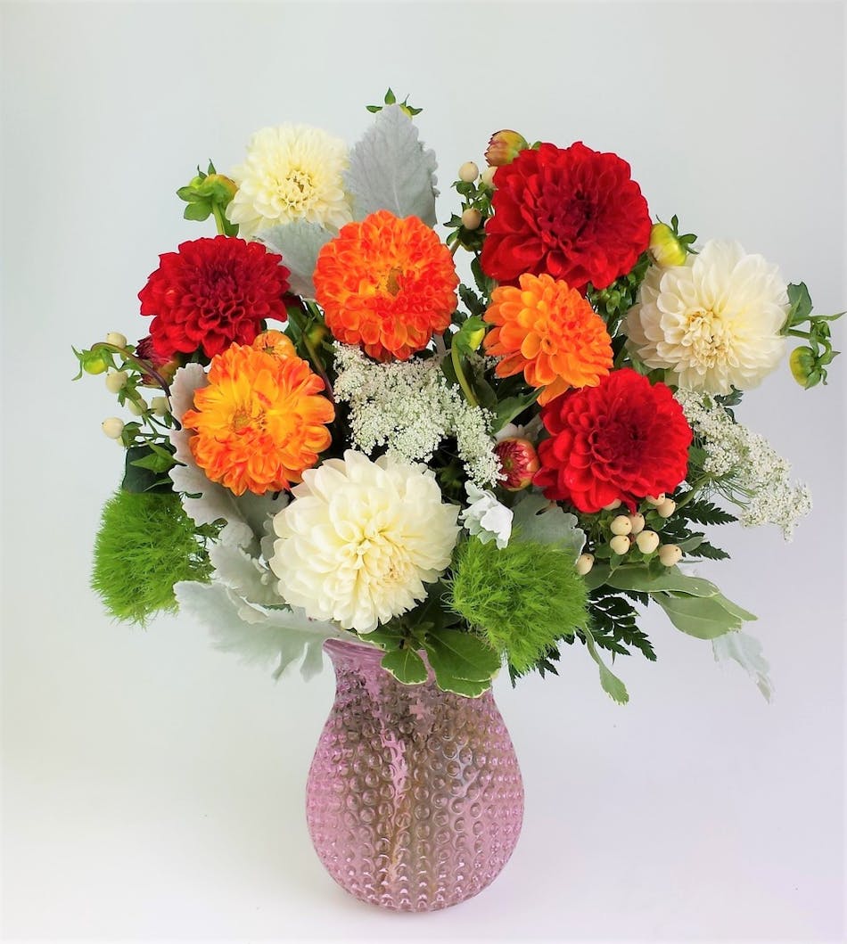Fresh Garden Dahlias combined with elegant garden textures and blossoms. Assorted Colors of Dahlias designed in a Clear Dimple textured Glass  Vase, .